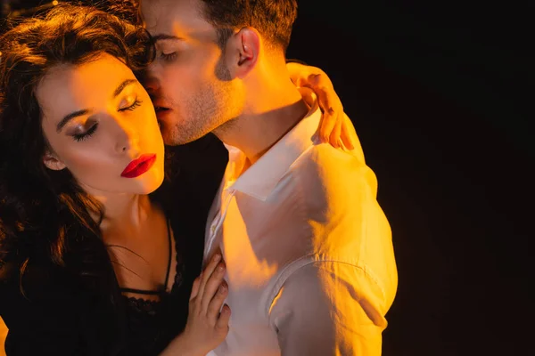 Hochwinkel-Ansicht von Mann im Hemd küsst Frau mit geschlossenen Augen isoliert auf schwarz — Stockfoto