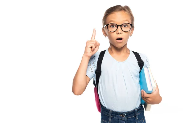 Colegiala en gafas sosteniendo libros mientras tiene idea aislado en blanco - foto de stock