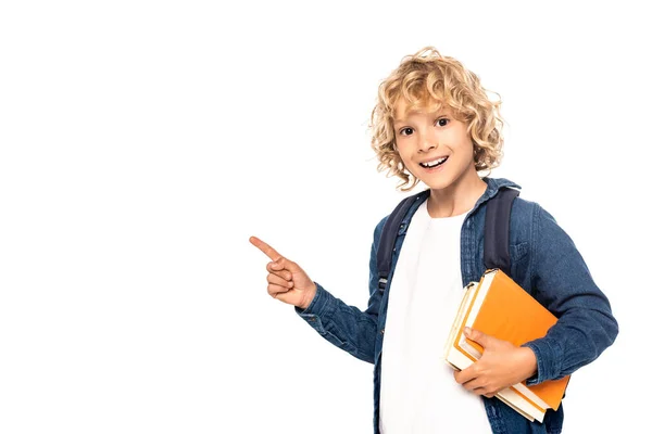 Colegial rubia sosteniendo libros y señalando con el dedo aislado en blanco - foto de stock