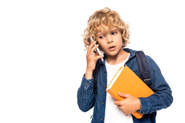 Neugieriges Schulkind hält Buch in der Hand und spricht auf Smartphone isoliert auf weißem Grund — Stockfoto