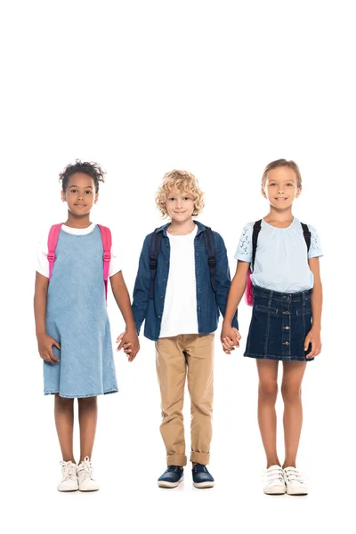 Blonde schoolboy holding hands with multicultural schoolgirls isolated on white — Stock Photo