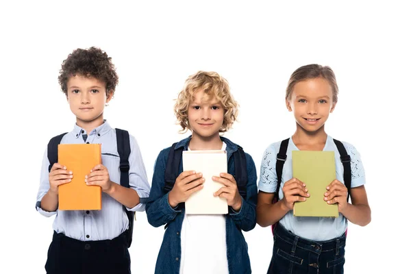 Lockige Schuljungen und Schulmädchen halten Bücher isoliert auf weiß — Stockfoto