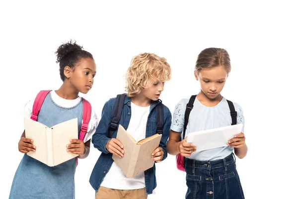 Afrikanisch-amerikanische Schulmädchen und blonde Schüler mit Büchern Blick auf digitale Tablet in den Händen von Klassenkamerad isoliert auf weiß — Stockfoto
