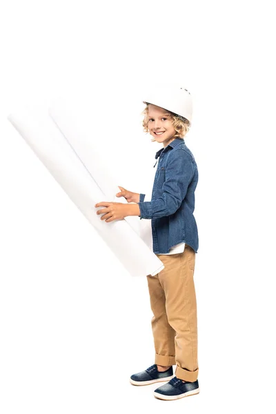 Niño rizado en casco de seguridad y traje de arquitecto sosteniendo plano y mirando a la cámara aislada en blanco - foto de stock