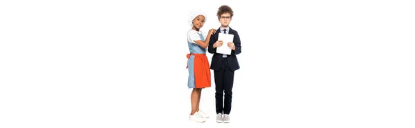 Tiro panorâmico de criança afro-americana tocando menino em óculos e terno segurando tablet digital isolado em branco — Fotografia de Stock