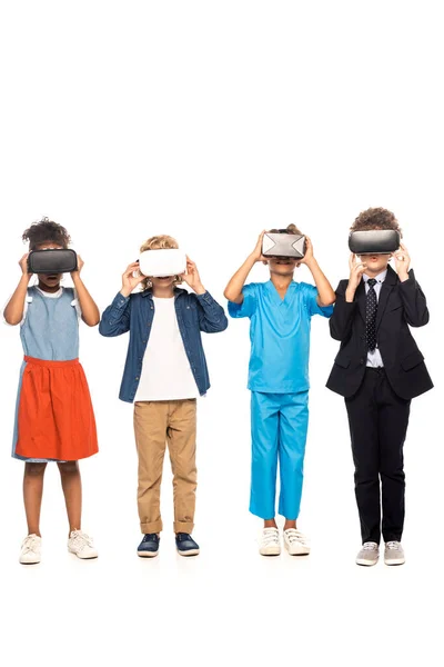 Niños multiculturales vestidos con disfraces de diferentes profesiones tocando auriculares de realidad virtual aislados en blanco - foto de stock