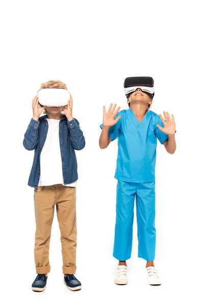 Niño tocando auriculares de realidad virtual mientras niño gesto aislado en blanco - foto de stock
