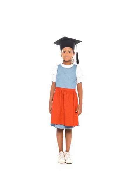 Niño afroamericano en gorra de graduación de pie aislado en blanco — Stock Photo