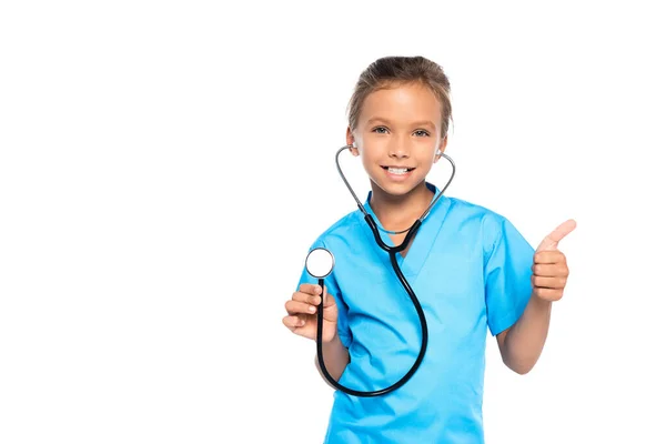 Kid in costume of doctor holding stethoscope while showing thumb up isolated on white — Stock Photo