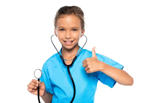 Child in costume of doctor holding stethoscope while showing thumb up isolated on white — Stock Photo