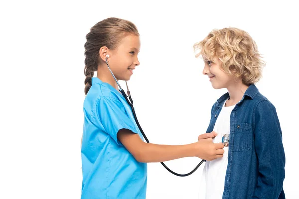 Vista laterale di bambino in costume di medico esaminando ragazzo biondo isolato su bianco — Foto stock