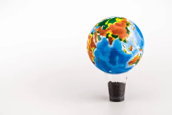 Земной шар на пластиковой чашке с землей на белом фоне — стоковое фото