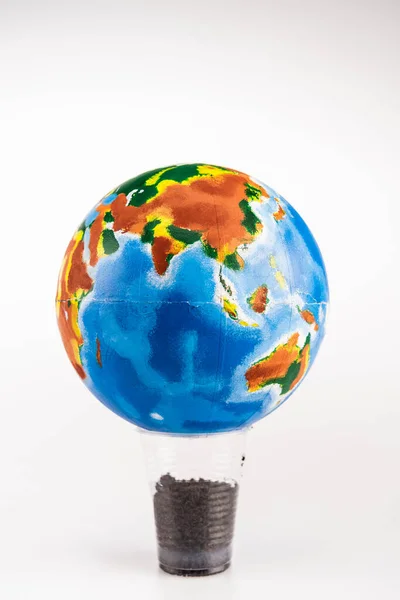 Земной шар на пластиковой чашке с землей на белом фоне — стоковое фото