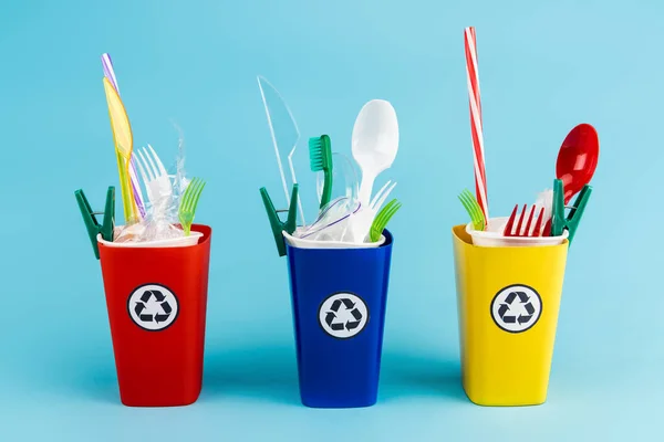 Bacs de recyclage multicolores avec du plastique sur fond bleu — Photo de stock