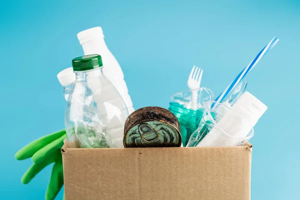 Пластиковые мусор и резиновые перчатки в картонной коробке изолированы на синий — стоковое фото