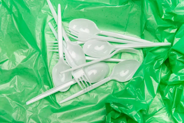 Vue du dessus des couverts jetables blancs sur la texture plastique verte — Photo de stock