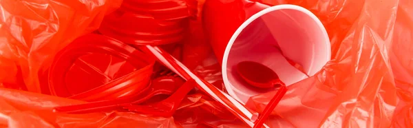 Objets jetables rouges sur la texture froissée en plastique, vue panoramique — Photo de stock