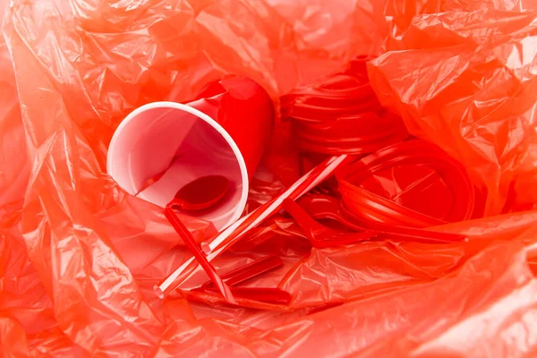 Objets jetables rouges sur texture froissée en plastique — Photo de stock