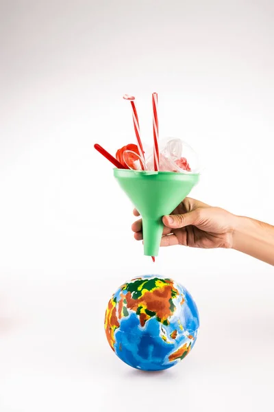 Vue recadrée de l'homme tenant entonnoir avec du plastique au-dessus du globe sur fond blanc — Photo de stock