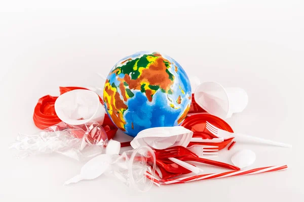 Plastic trash scattered around globe on white background — Stock Photo