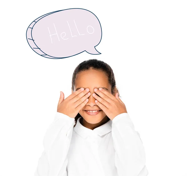 African schoolgirl smiling while covering eyes with hands isolated on white, speech bubble with hello lettering illustration — Stock Photo