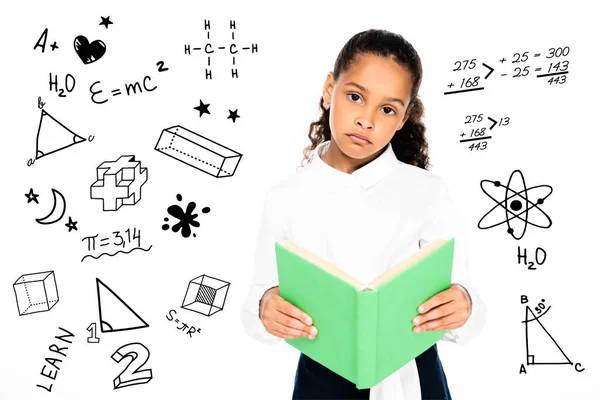 Upset african american schoolgirl looking at camera while holding book isolated on white, educational illustration — Stock Photo