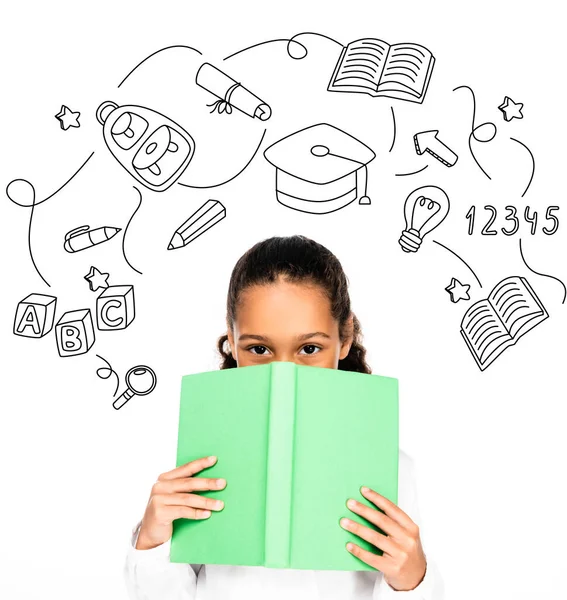 African american schoolgirl looking at camera while holding book near face isolated on white, educational illustration — Stock Photo