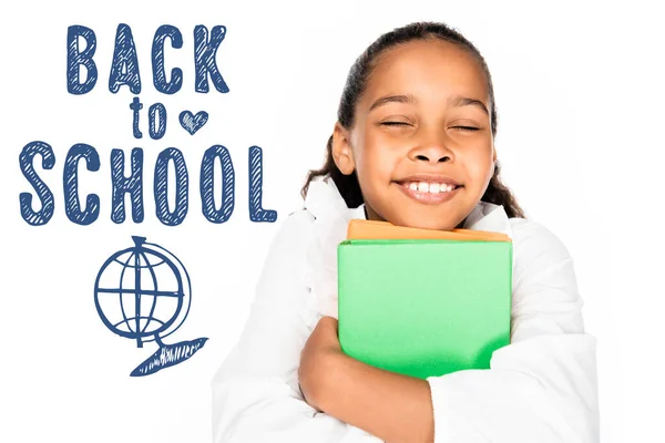 African american schoolgirl smiling with closed eyes while holding books isolated on white, back to school illustration — Stock Photo