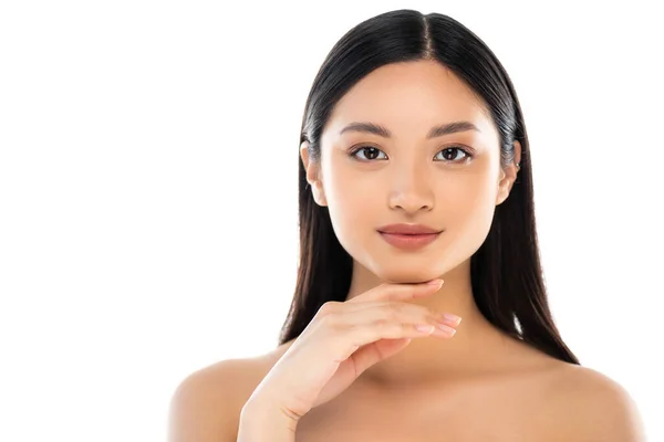 Giovane donna asiatica guardando la fotocamera e toccando il viso isolato su bianco — Foto stock