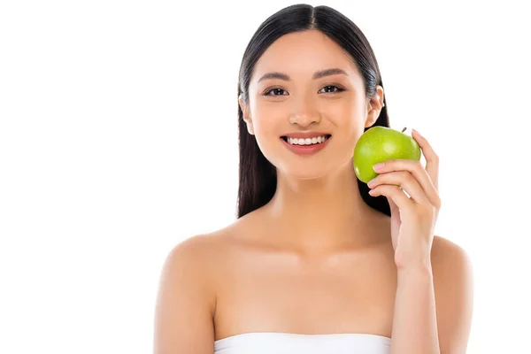 Возбужденная молодая азиатка смотрит в камеру и держит яблоко изолированным на белом — стоковое фото