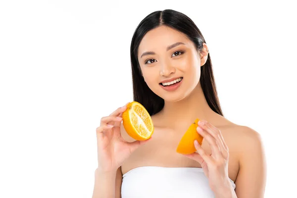 Brunette asian woman looking at camera while holding halves of juicy orange isolated on white — Stock Photo
