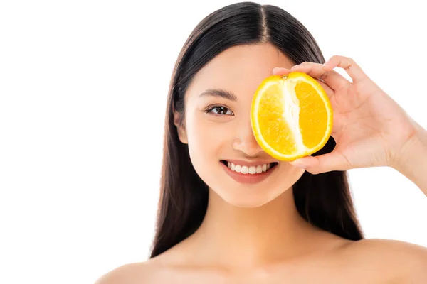 Brunette asian woman covering eye with half of ripe orange isolated on white — Stock Photo