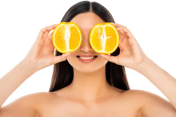 Brunette woman covering eyes with halves of juicy orange isolated on white — Stock Photo