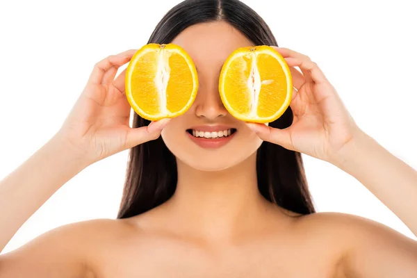 Naked brunette woman covering eyes with halves of ripe orange isolated on white — Stock Photo