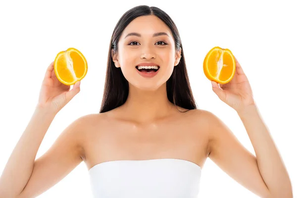 Animado ásia mulher olhando para câmera enquanto segurando metades de suculento laranja isolado no branco — Fotografia de Stock