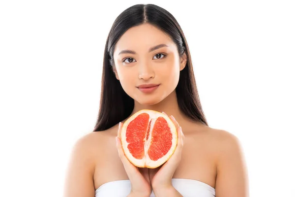 Jeune asiatique femme regarder caméra tout en tenant la moitié de pamplemousse isolé sur blanc — Photo de stock