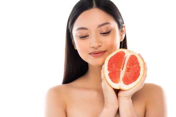 Naked asian woman holding half of ripe, juicy grapefruit near face isolated on white — Stock Photo