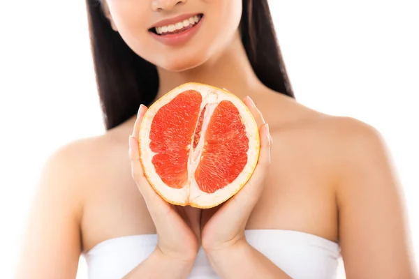 Vista recortada de la mujer sosteniendo la mitad de pomelo jugoso aislado en blanco - foto de stock