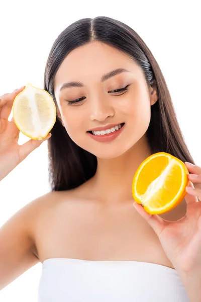 Joven asiático mujer celebración mitades de limón y naranja aislado en blanco - foto de stock