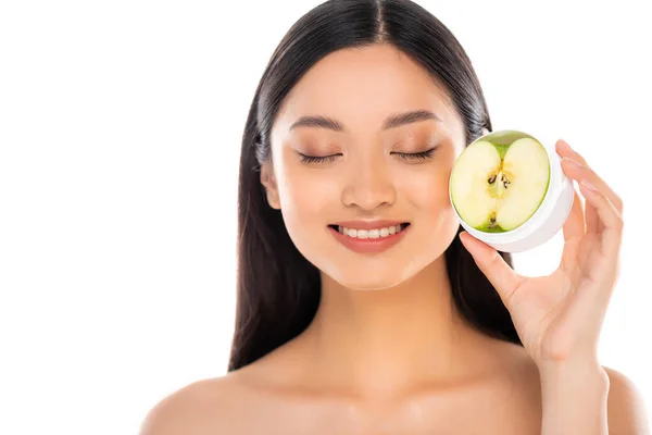Оголена азіатська жінка з закритими очима тримає половину зеленого яблука біля обличчя ізольовано на білому — стокове фото