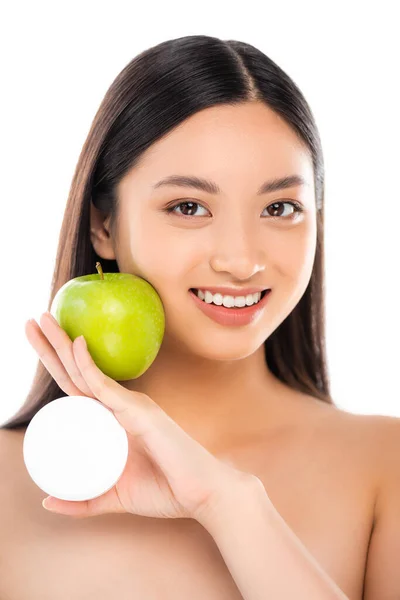 Nudo asiatico donna holding maturo verde mela e cosmetico crema vicino faccia isolato su bianco — Foto stock