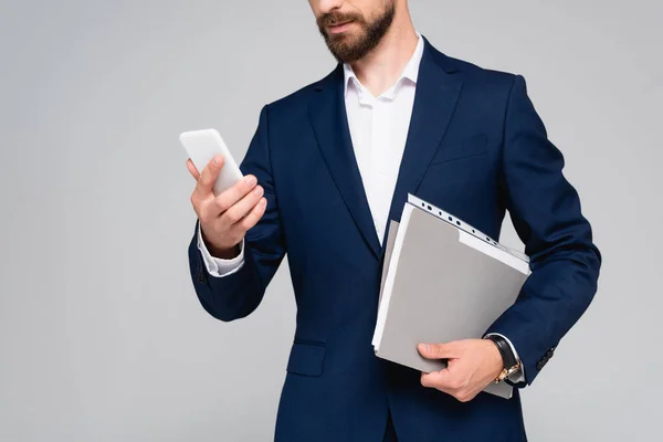 Vista recortada del hombre de negocios en blazer azul con teléfono inteligente y documentos aislados en gris - foto de stock