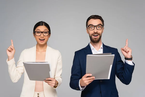 Excited couple of interracial business colleagues showing idea gesture while holding folders isolated on grey — Stock Photo