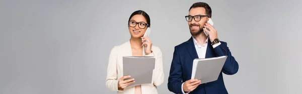 Panoramisches Konzept von interrassischen Geschäftsleuten, die auf Mobiltelefonen sprechen, während sie Ordner isoliert auf grau halten — Stockfoto