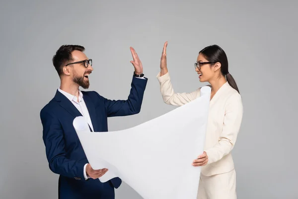 Ein paar Geschäftskollegen halten ein weißes Plakat in die Höhe und geben High Five isoliert auf grau — Stockfoto