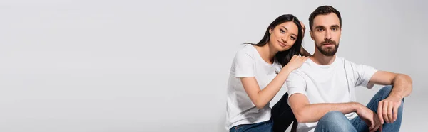 Horizontales Konzept einer asiatischen Frau, die sich auf die Schulter ihres Freundes stützt, während sie auf Weiß sitzt — Stockfoto