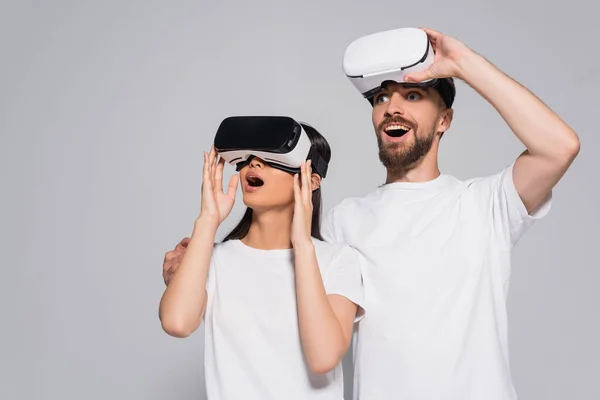 Excited woman using vr headset near bearded man looking away isolated on grey — Stock Photo