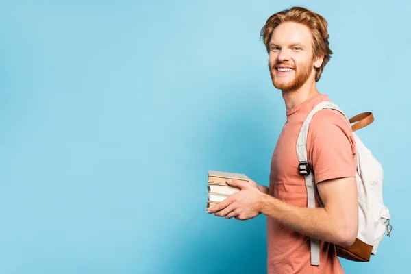 Bärtige Studentin hält Bücher in der Hand und blickt in die Kamera — Stockfoto