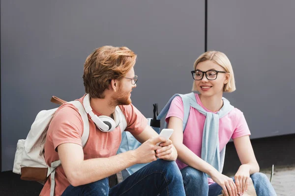 Students in glasses sitting and looking at each other outside — Stock Photo