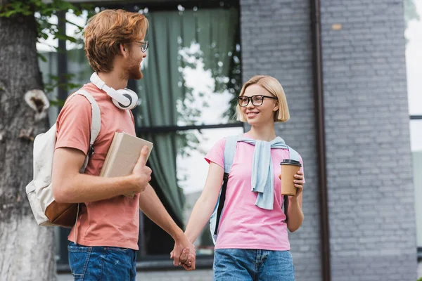 Students in glasses holding hands and looking at each other — Stock Photo